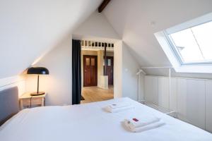 een slaapkamer met een wit bed en een dakraam bij General Sixty-Seven by Romy&Travis in Brugge