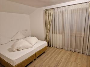 a white bedroom with a bed and a window at Apartment Aghel in Ortisei