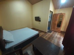 BhowāliにあるNainital Cottage And Resortの小さなベッドルーム(ベッド1台、テレビ付)