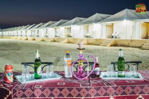 una mesa con un jarrón rosa y botellas en ella en ARMAN DESERT RESORT, en Sām