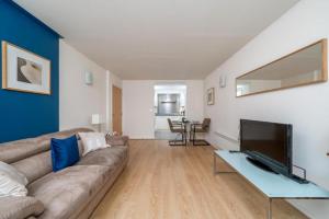 sala de estar con sofá y TV de pantalla plana en Luxury 1 Bed Apartment Close To Excel & o2 en Londres