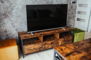 uma televisão num suporte de madeira com uma televisão por cima em Nowy Złocień Comfort Apartment em Cracóvia
