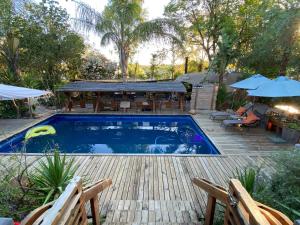 a swimming pool with a deck and a patio with umbrellas at Karoozin Village in Oudtshoorn