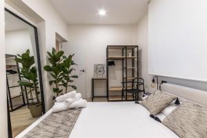 ein Schlafzimmer mit einem weißen Bett und einer Pflanze in der Unterkunft El Kallejón By Kabia Gestión in Bilbao