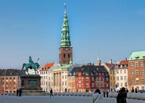Un gruppo di persone che camminano per una città con una torre dell'orologio di Deluxe Flat at Perfect Location a Copenaghen