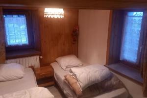 two beds in a room with two windows at Maison de village - montagne in Landry