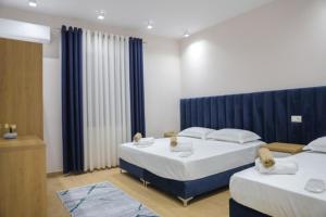 1 dormitorio con 2 camas y cortinas azules en Hotel Krial en Berat