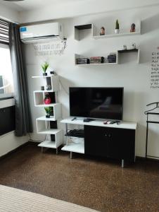 sala de estar con TV y estanterías blancas en Shaddai Alojamientos, en Salta