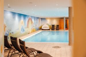 a large swimming pool in a room with chairs around it at Hotel Glockenstuhl in Westendorf