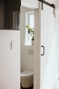 Baño con aseo a través de una puerta blanca en 107 Dorpstraat Boutique Hotel, en Stellenbosch