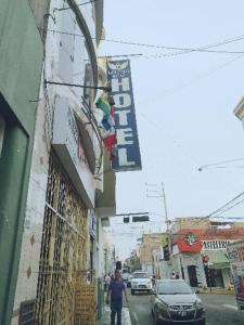Un uomo che cammina per una strada accanto a un edificio di Hotel lucero real 1 a Tacna
