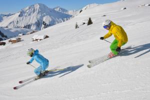2 personnes font du ski sur une piste enneigée dans l'établissement Haus Sonnberg, à Mellau