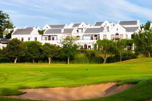 een golfbaan met een groot wit huis op de achtergrond bij De Zalze Lodge in Stellenbosch