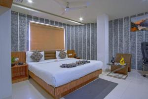 a bedroom with a large bed and a window at Hotel Limra in Surat