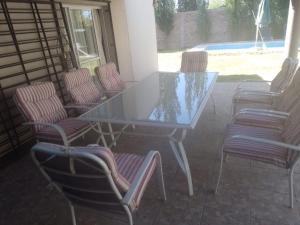 - une table et des chaises en verre sur la terrasse dans l'établissement Casa amplia con pileta 9 personas, à Luján de Cuyo