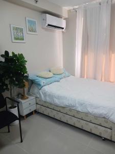 a white bedroom with a bed and a window at NJC Staycation in Suba