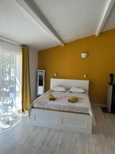a bedroom with a white bed with a yellow wall at VILLA AVEC PISCINE in Néoules