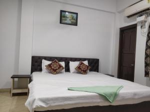 a bedroom with a bed with white sheets and pillows at Adarsh Hotel in Port Blair