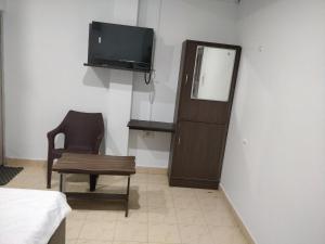 a room with a tv and a chair and a table at Adarsh Hotel in Port Blair