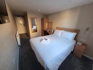 ein Hotelzimmer mit einem großen weißen Bett und einem Spiegel in der Unterkunft Cavendish Hotel in Exmouth