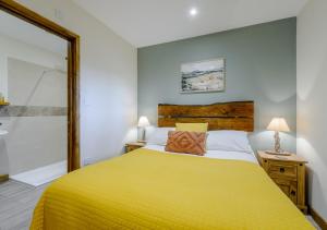 a bedroom with a yellow bed and a bathroom at Squirrel in Postling