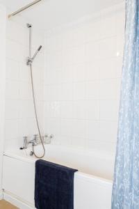 a bathroom with a bath tub with a blue shower curtain at Cosy Apartment near Nottingham City Centre in Nottingham