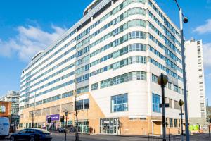 a large white building with a car parked in front of it at Cosy Apartment near Nottingham City Centre in Nottingham