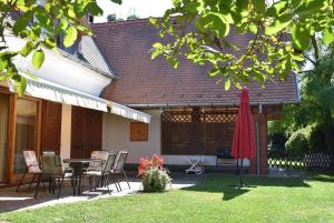 un patio con mesa, sillas y sombrilla en Berek Ház, en Balatonberény