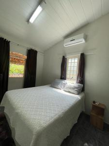 a bedroom with a white bed with a window at Sítio Gran Royalle in Sete Lagoas