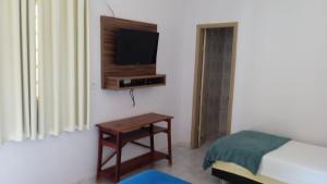 a bedroom with a bed and a table and a tv at Hotel Solyara in Baixão