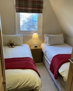 two beds in a small room with a teddy bear sitting between them at Lodge 24 in Spean Bridge