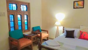 1 dormitorio con 1 cama, 2 sillas y escritorio en Jungle Heritage, en Paliā Kalān