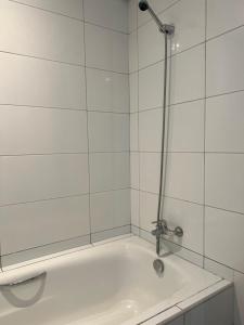 a bath tub with a shower in a white tiled bathroom at برج داماك in Jeddah