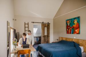 twee vrouwen in een slaapkamer met een bed en een tafel met een laptop bij B&B Art.14 in Morkhoven