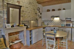 - une cuisine avec une table et un mur en pierre dans l'établissement La maison du facteur, à Saint-Denis-dʼOléron