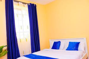 1 dormitorio con 1 cama con cortinas azules y ventana en Naivasha 2 Bedroom Rated Best, en Naivasha