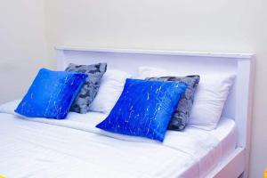 Una cama blanca con cuatro almohadas azules. en Naivasha 2 Bedroom Rated Best, en Naivasha
