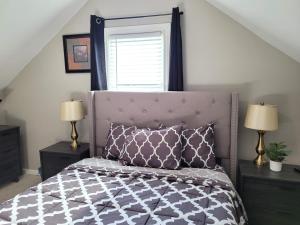 een slaapkamer met een bed, 2 lampen en een raam bij Brand new house with private bath in each room in West Seneca