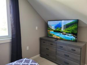 a tv sitting on a dresser in a bedroom at Brand new house with private bath in each room in West Seneca