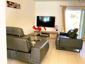 - un salon avec deux canapés en cuir et une télévision à écran plat dans l'établissement Charme du Nord 2, à Sainte-Clotilde