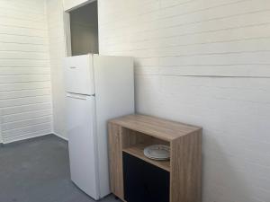 een witte koelkast en een houten standaard met een plaat bij Bonheur en Centre-Ville : Réservez votre Évasion F2 à Basse-Terre in Basse-Terre