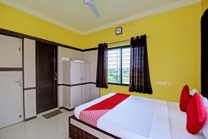a bedroom with a bed with yellow walls and red pillows at Flagship JMD Upasana 2 in Kolkata