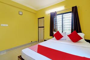 a bedroom with a bed with red and white pillows at Flagship JMD Upasana 2 in Kolkata