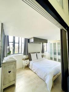 a bedroom with a large white bed and windows at Le Loft -Superbe volume- in Saint-Étienne
