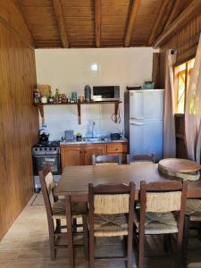 a kitchen with a wooden table and a refrigerator at Chalés Altos Da Montanha -K2 in Bom Jardim da Serra