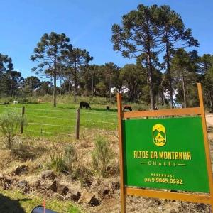 a green sign in a field with animals in the background at Chalés Altos Da Montanha -K2 in Bom Jardim da Serra +1 photo