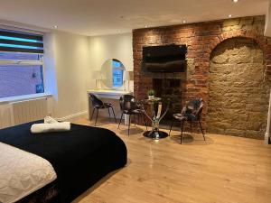 um quarto com uma parede de tijolos, uma cama, uma mesa e cadeiras. em Luxury Grand Studio Apartment @3 em Barnsley