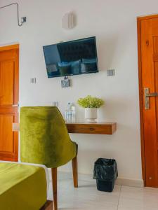 een kamer met een groene stoel en een tv aan de muur bij Sunset Villa in Waskaduwa