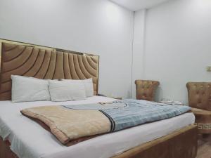 Schlafzimmer mit einem großen Bett mit einem Kopfteil aus Holz in der Unterkunft Safari Hotel in Lahore