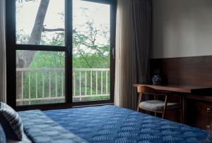 una camera con letto, scrivania e finestra di Villa Olives, Vanashraya a Jaipur